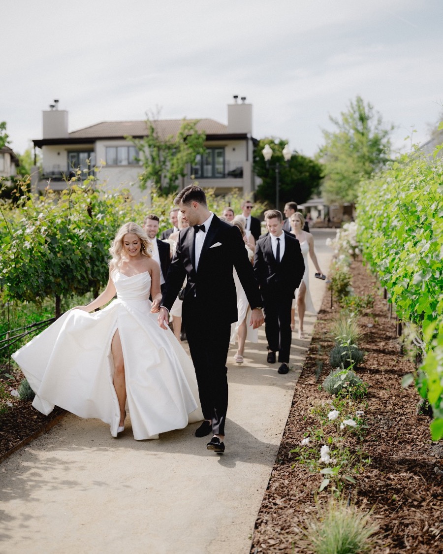 A bridal party walking a vineyard path together, photographed by Paul Von Rieter